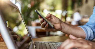 Student is seen using smartphone and laptop. (Getty Images)