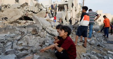 Palestinian children sit amidst the rubble as others inspect under the rubble of a building destroyed by Israeli strikes in Khan Younis in the southern Gaza Strip, Palestine, Oct. 17, 2023. (Reuters Photo)
