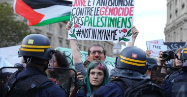 A Jewish French protester holds a placard reading &quot;Jewish and anti-Zionist against the genocide of the Palestinians, not in my name&quot; as protesters face riot police officers during a demonstration in support of Palestinians, Place de la Republique, Paris, France, Oct. 19, 2023. (AFP Photo)