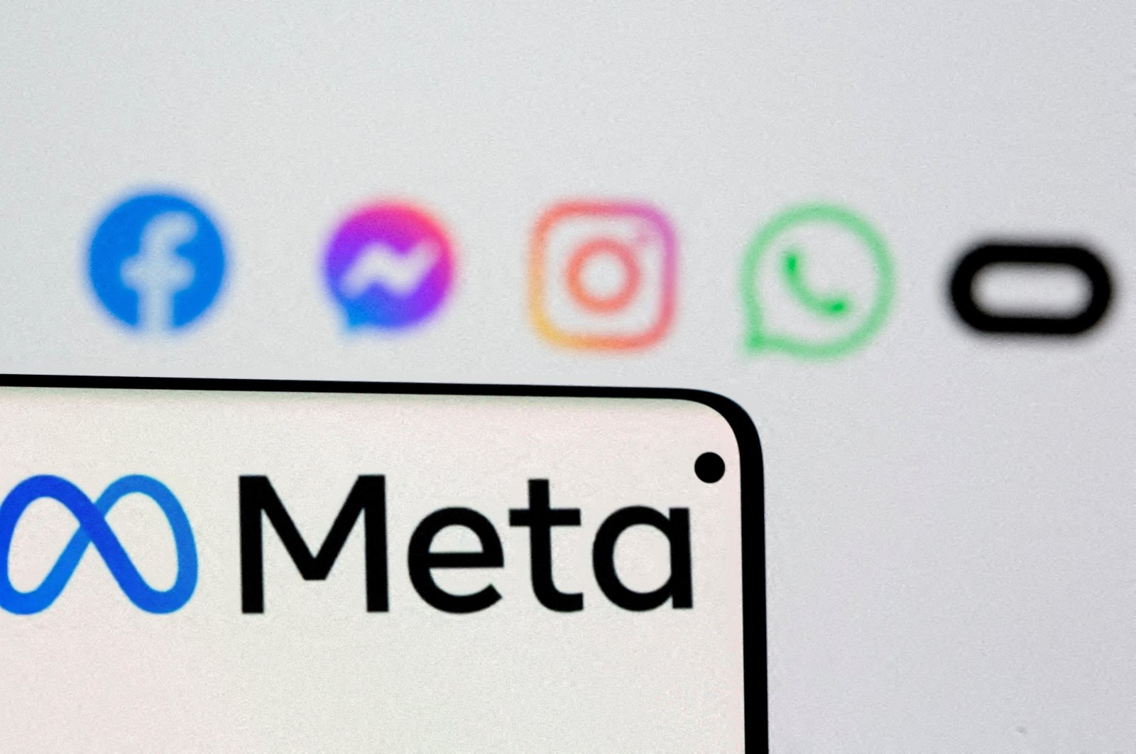 Facebook&#039;s new rebrand logo Meta is seen on smartphone in front of a displayed logo of Facebook, Messenger, Instagram, WhatsApp and Oculus in this illustration picture taken Oct. 28, 2021. (Reuters Photo)