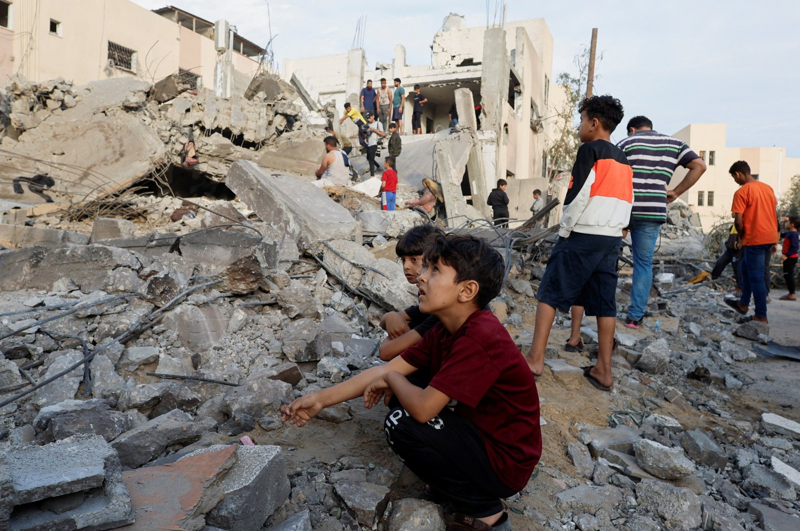 Palestinian children sit amidst the rubble as others inspect under the rubble of a building destroyed by Israeli strikes in Khan Younis in the southern Gaza Strip, Palestine, Oct. 17, 2023. (Reuters Photo)