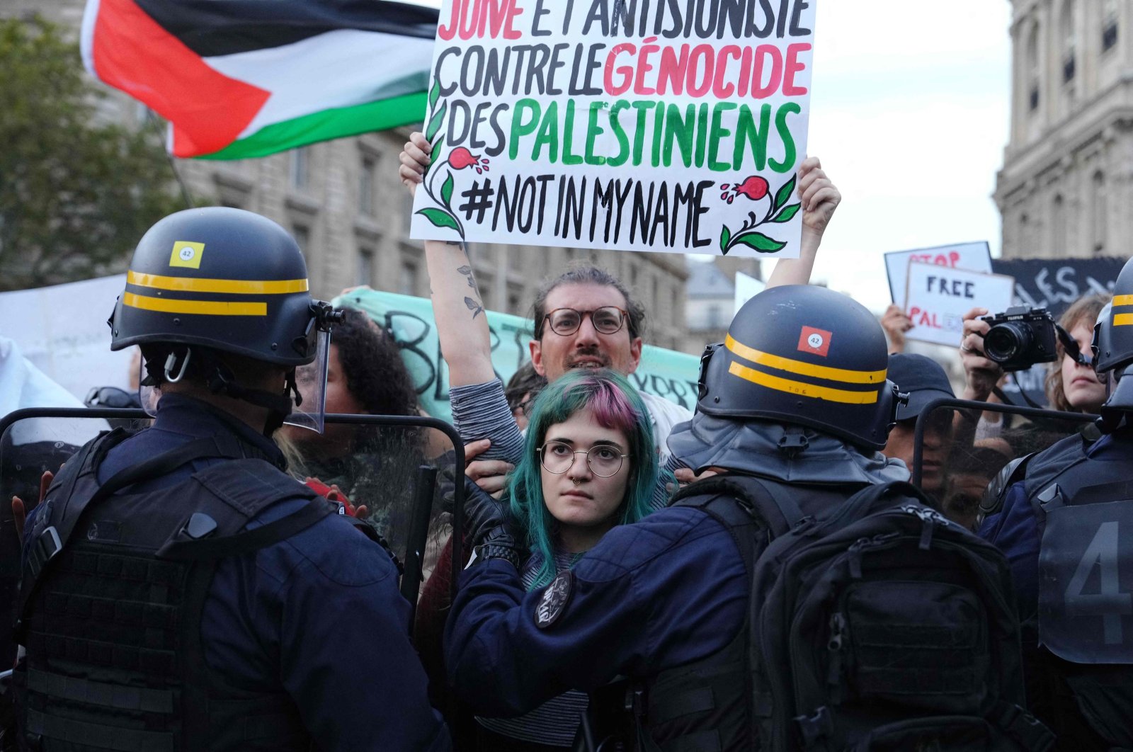 A Jewish French protester holds a placard reading &quot;Jewish and anti-Zionist against the genocide of the Palestinians, not in my name&quot; as protesters face riot police officers during a demonstration in support of Palestinians, Place de la Republique, Paris, France, Oct. 19, 2023. (AFP Photo)
