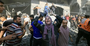 A Palestinian woman reacts as others rush to look for victims in the rubble of a building following an Israeli strike in Khan Younis in the southern Gaza Strip, Oct. 17, 2023. (AFP Photo)