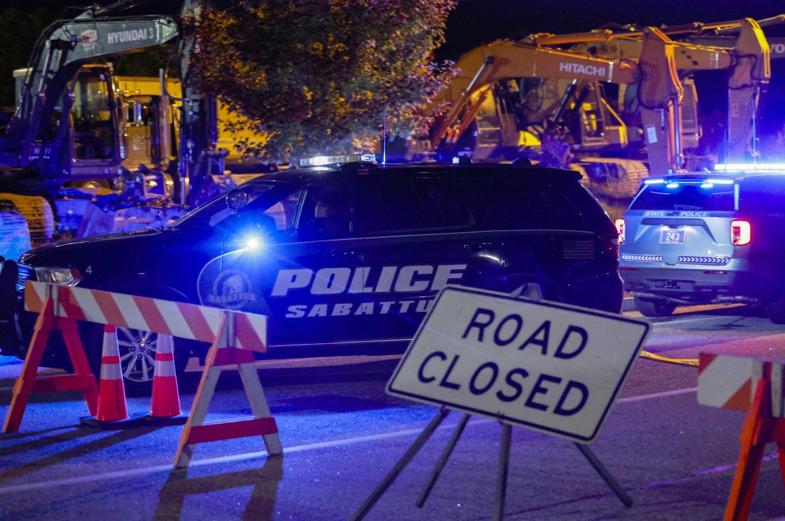 A police car drives past a roadblock sign on the road leading to Schemengees bar where a man reportedly opened fire killing and injuring numerous people in Lewiston, Maine, U.S., Oct. 25 2023. (EPA Photo)