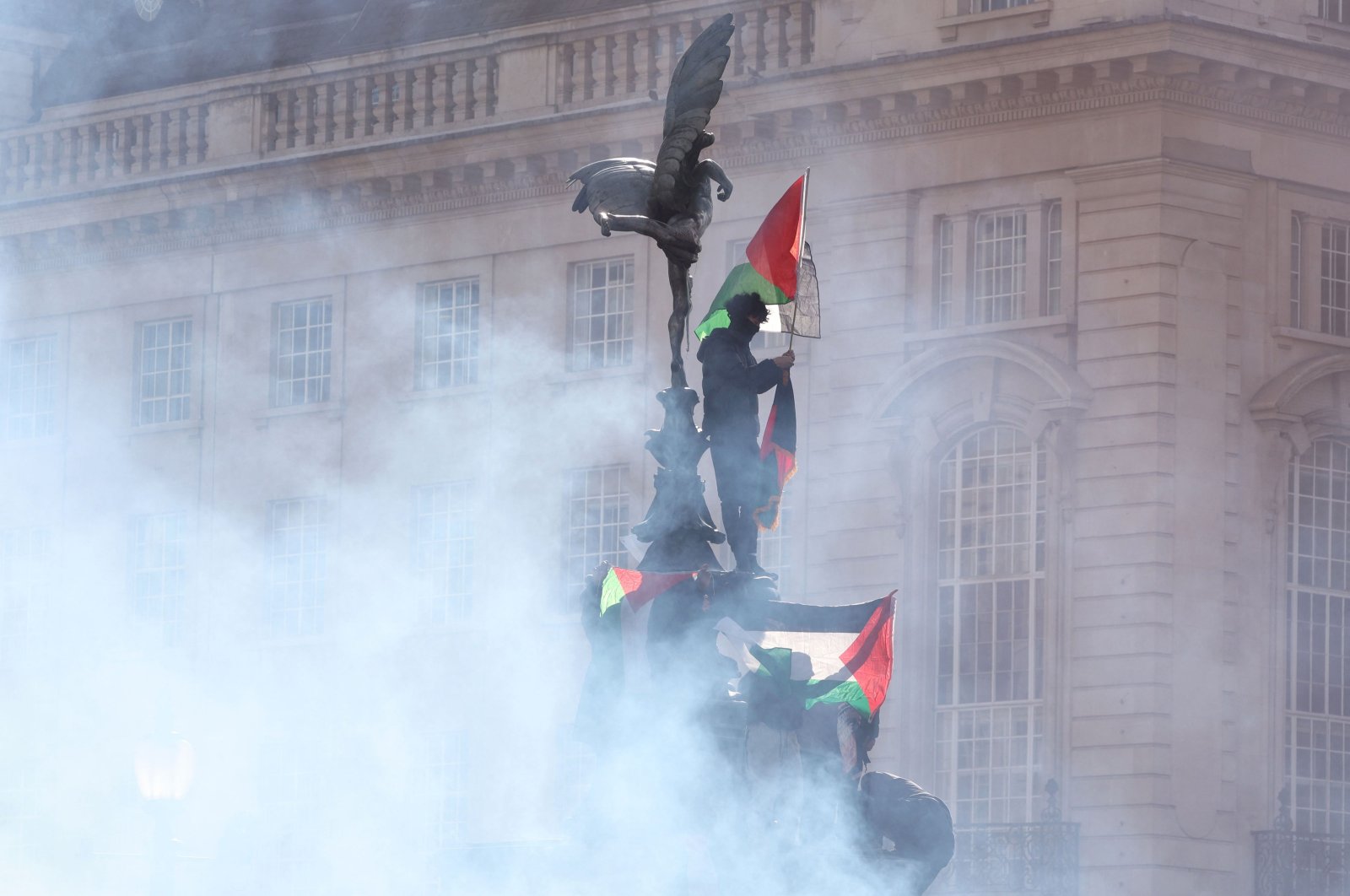 Protesters waving Palestinian flags climb the Eros statue at Piccadilly Circus during a &quot;March For Palestine,&quot; part of a pro-Palestinian national demonstration, organized by the Palestine Solidarity Campaign, Friends of Al-Aqsa, Stop the War Coalition, the Muslim Association of Britain, the Palestinian Forum in Britain and CND, London, U.K., Oct. 14, 2023. (AFP Photo)