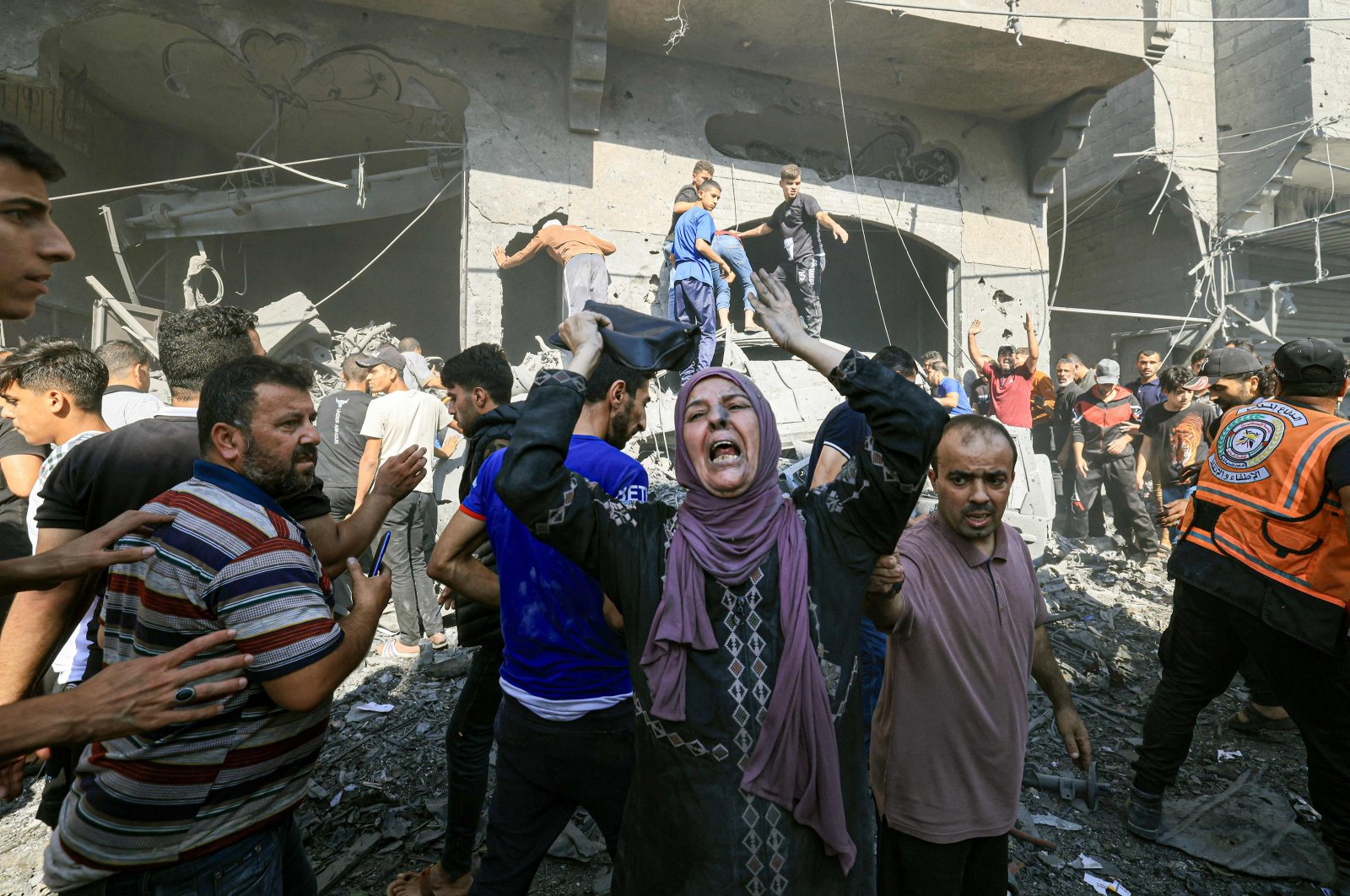 A Palestinian woman reacts as others rush to look for victims in the rubble of a building following an Israeli strike in Khan Younis in the southern Gaza Strip, Oct. 17, 2023. (AFP Photo)