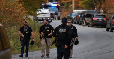 Law enforcement officials gather in the road leading to the home of the suspect being sought in connection with two mass shootings, Bowdoin, Maine, U.S., Oct. 26, 2023. (Getty Images via AFP Photo)