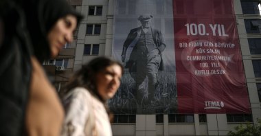 Two women pass by a poster in the backdrop showing an image of the Republic of Türkiye&#039;s founder Mustafa Kemal Atatürk, to commemorate the 100-year anniversary of the Republic, in Istanbul, Türkiye, Oct. 25, 2023. (AP Photo)