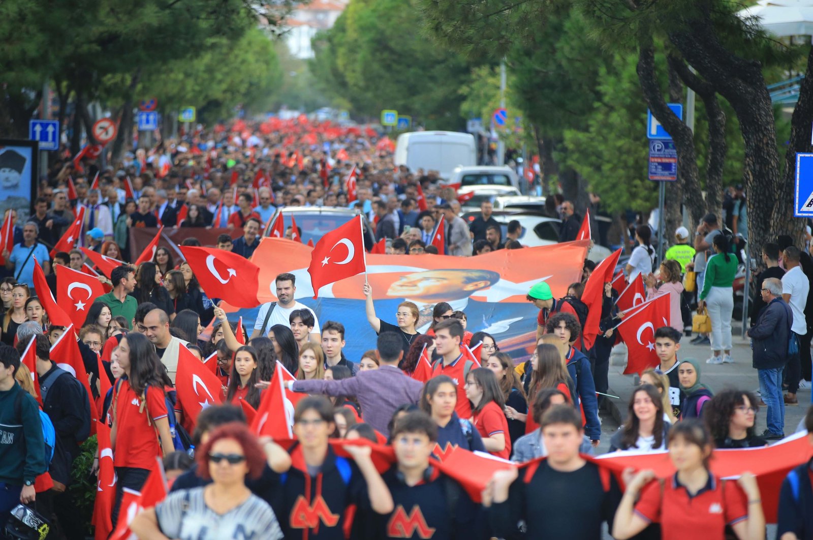 People walk with Turkish flags and a giant poster of Atatürk during the &quot;Republic March&quot; in Muğla, southwestern Türkiye, Oct. 23, 2023. (AA Photo)