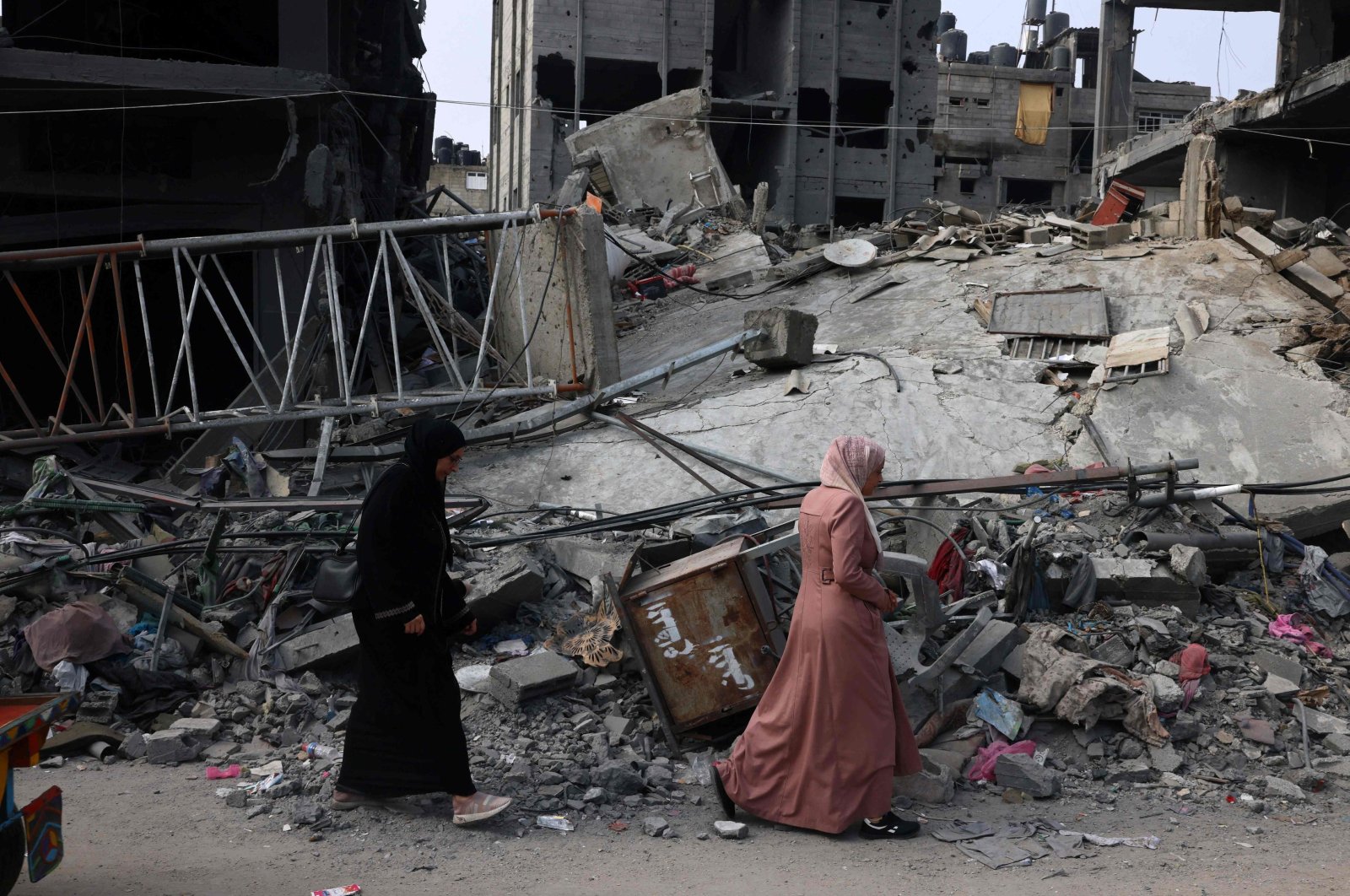 Women walk past a destroyed building in the aftermath of Israeli bombing in Rafah in the southern Gaza Strip, Palestine, Oct. 28, 2023. (AFP Photo)