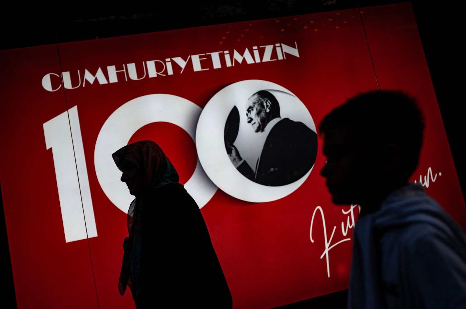 A woman and a boy walk in front of a banner ahead of celebrations marking the 100th anniversary of the Turkish Republic in Edirne, western Türkiye, Oct. 26, 2023. (AFP Photo)
