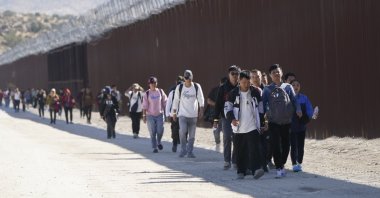 A group of people, including many from China, walk along the wall after crossing the border with Mexico to seek asylum, near Jacumba, California, U.S., Oct. 24, 2023. (AP Photo)