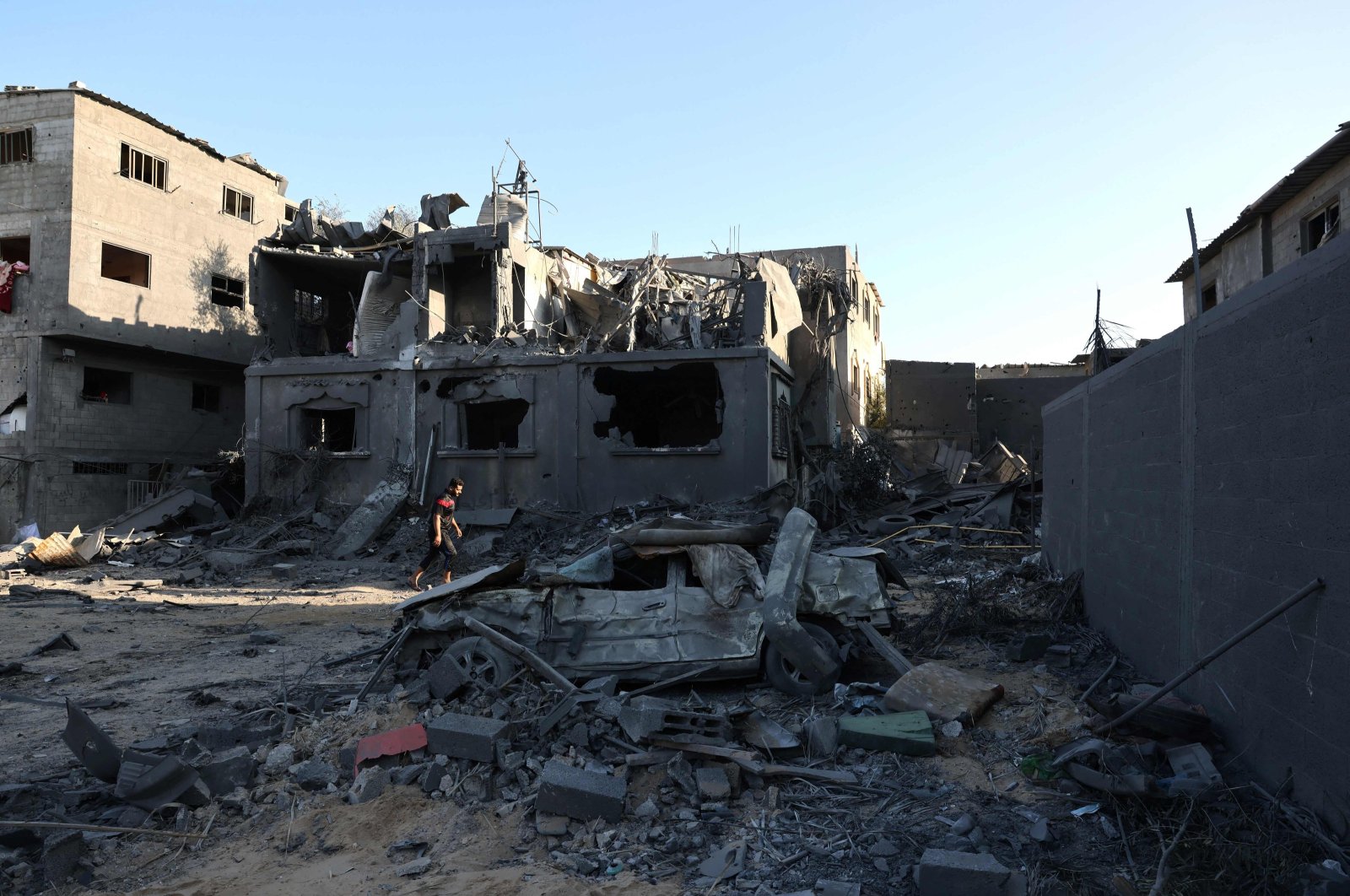A Palestinian man walks past a destroyed home and vehicle the day after an Israeli airstrike on the Nuseirat refugee camp, in the central Gaza Strip, Palestine, Oct. 30, 2023. (AFP Photo)