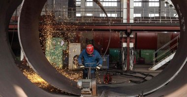 An employee works on a large construction equipment at a factory in Haian city, in China's eastern Jiangsu province, China, Oct. 16, 2023. (AFP Photo)