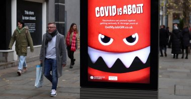 People walk past an advert warning about COVID-19 in Manchester, Britain, Nov. 26, 2022. (Reuters Photo)