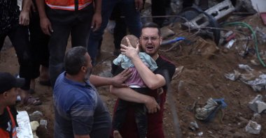 A Palestinian man cries while holding a dead child who was found under the rubble of a destroyed building following Israeli airstrikes in Nusseirat refugee camp, central Gaza Strip, Palestine, Oct. 31, 2023. (AP Photo)