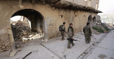 PKK terrorists walk in the damaged streets of Sinjar, Iraq, Jan. 29, 2015. (AP Photo)