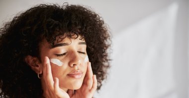 A woman applies cream to her face. (Getty Images Photo)