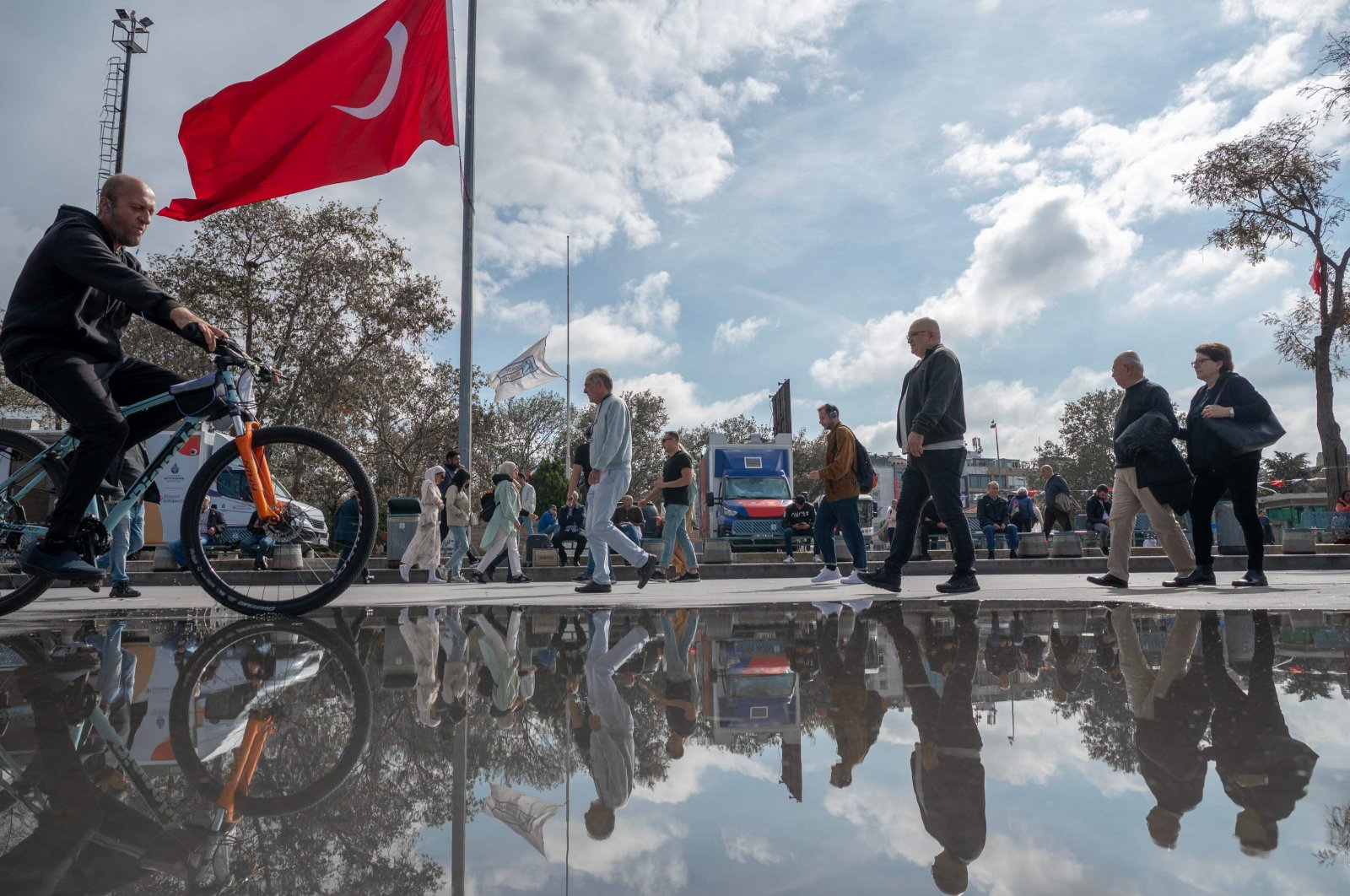 People walk past a Turkish flag at half-mast in Istanbul, Türkiye, Oct. 19, 2023. (AFP Photo)