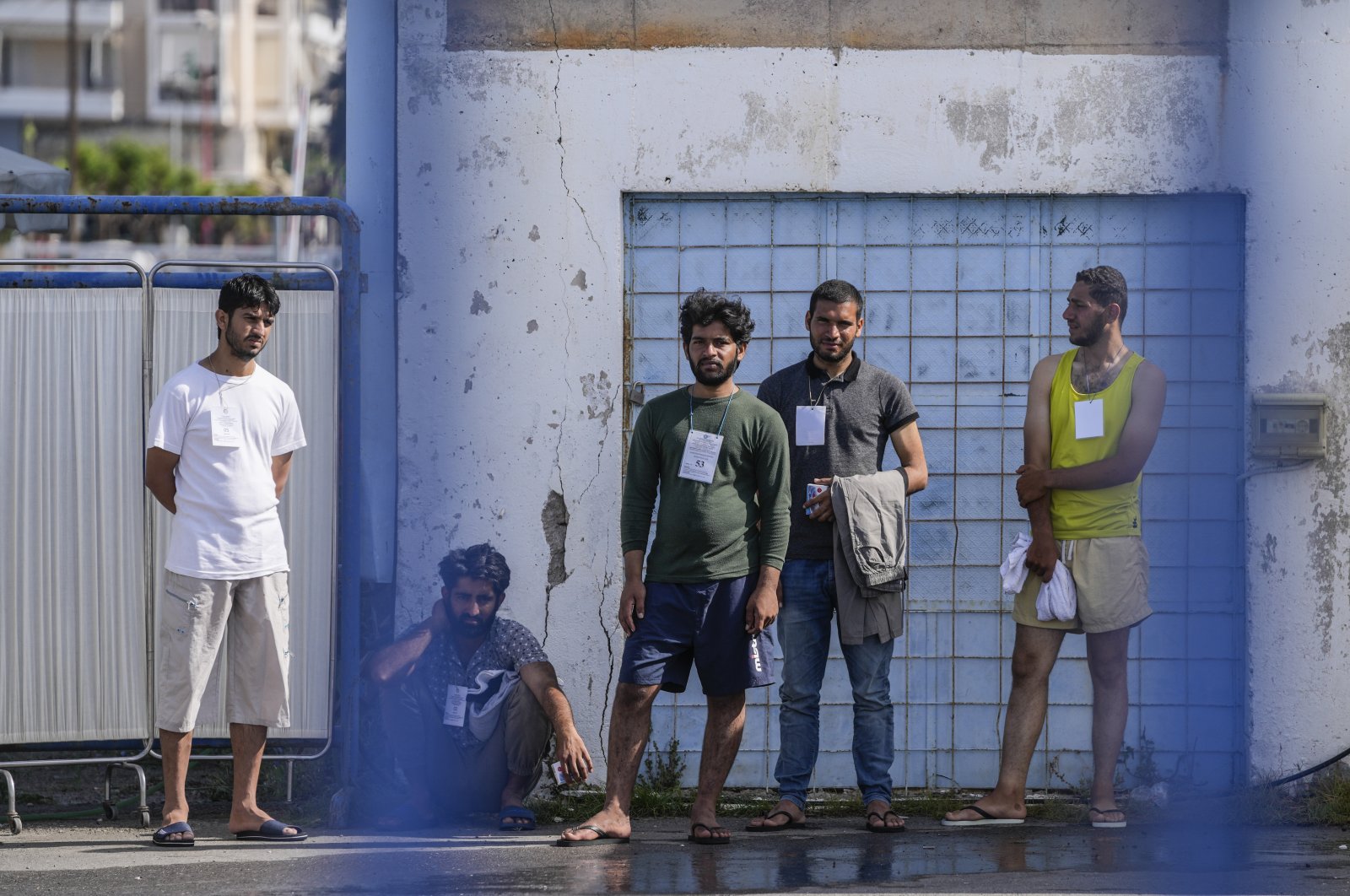 Survivors of a deadly migrant shipwreck stand outside a warehouse at the port in Kalamata town, about 240 kilometers (150 miles) southwest of Athens, Greece, Thursday, June 15, 2023. (AP Photo)