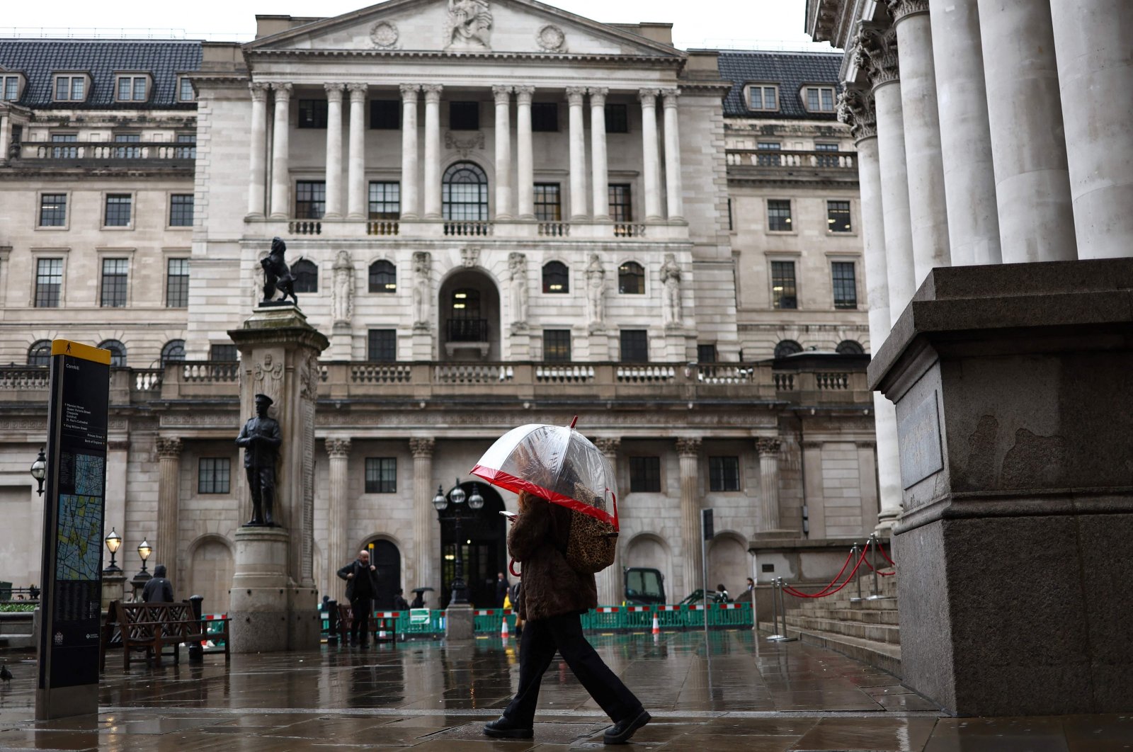 A pedestrian with an umbrella walks by the Bank of England building and Stock Exchange building, in the financial district, central London, U.K., Nov. 2, 2023. (AFP Photo)