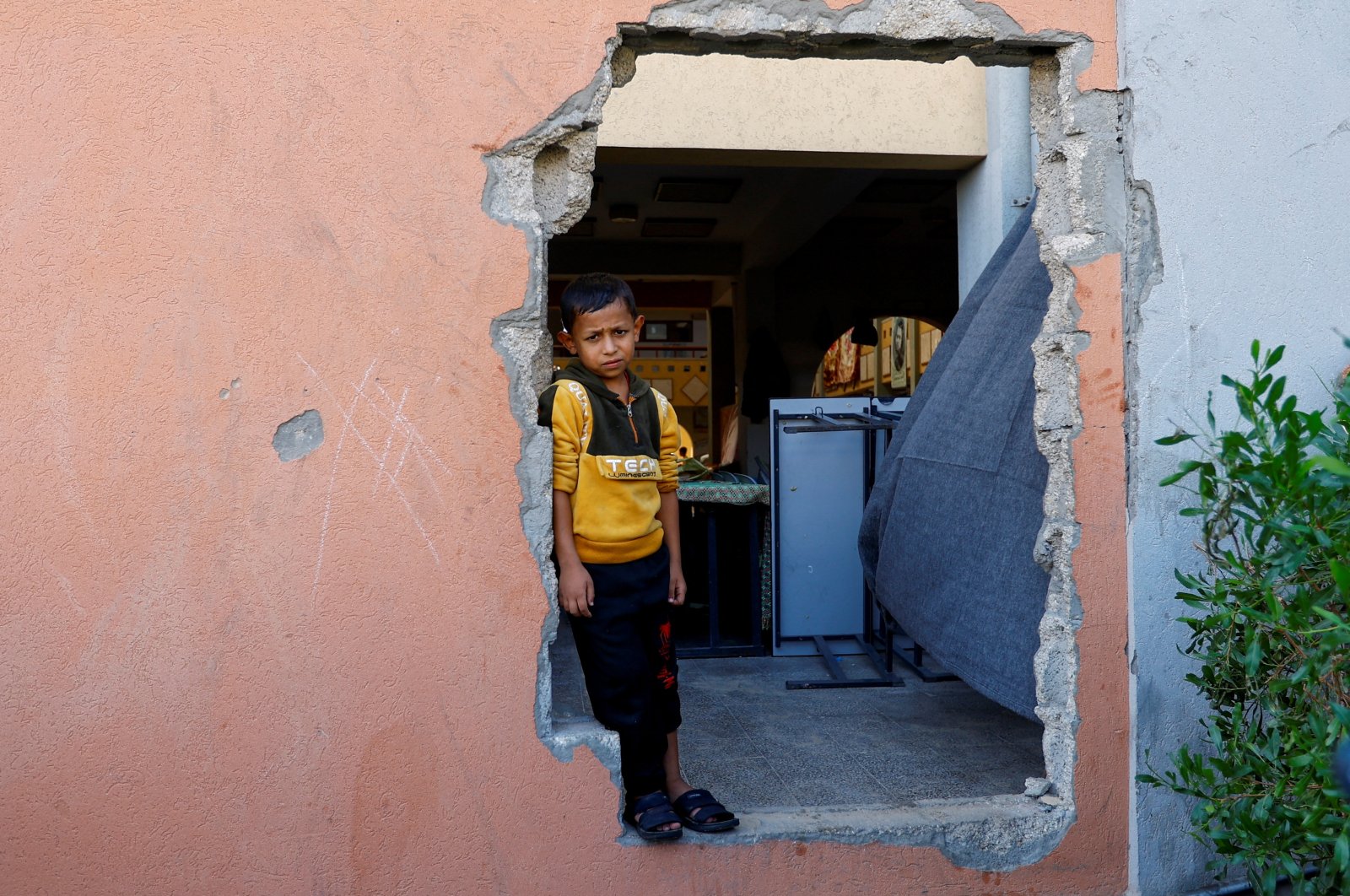 A Palestinian boy looks out of a hole in the wall, at a school turned to a shelter, in Khan Younis, southern Gaza Strip, Palestine, Oct. 31, 2023. (Reuters Photo)