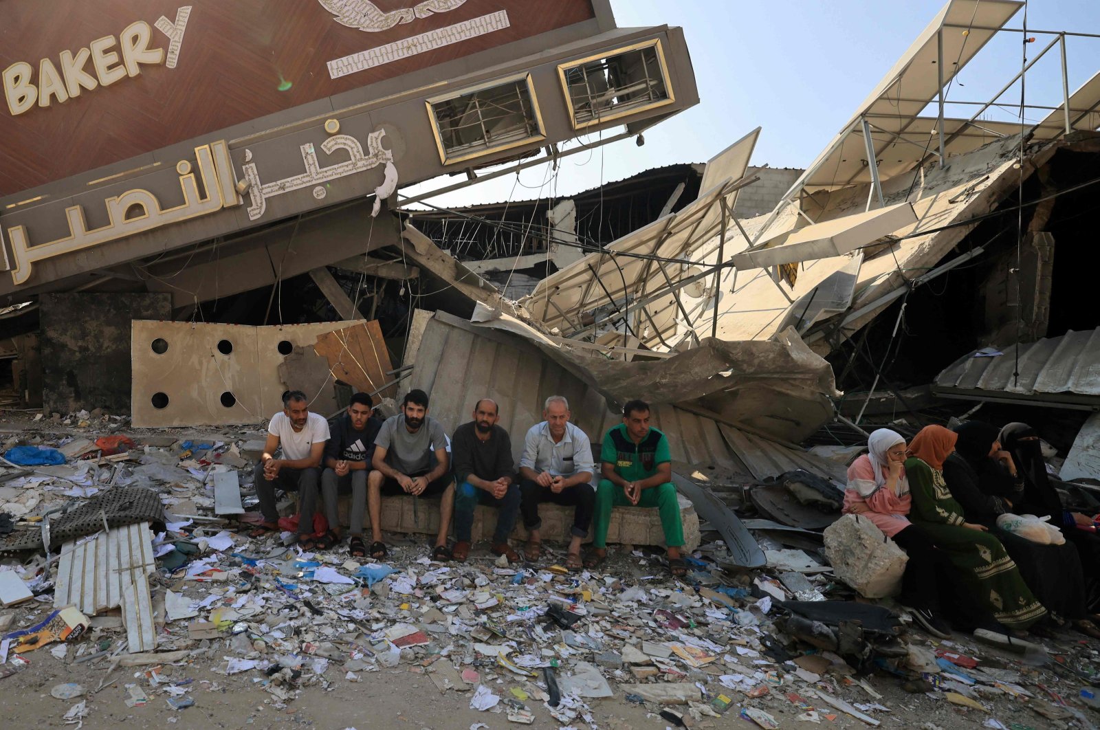 People sit in front of a bakery that was partially destroyed in an Israeli strike, in the Nuseirat refugee camp in the central Gaza Strip, Palestine, Nov. 2, 2023. (AFP Photo)