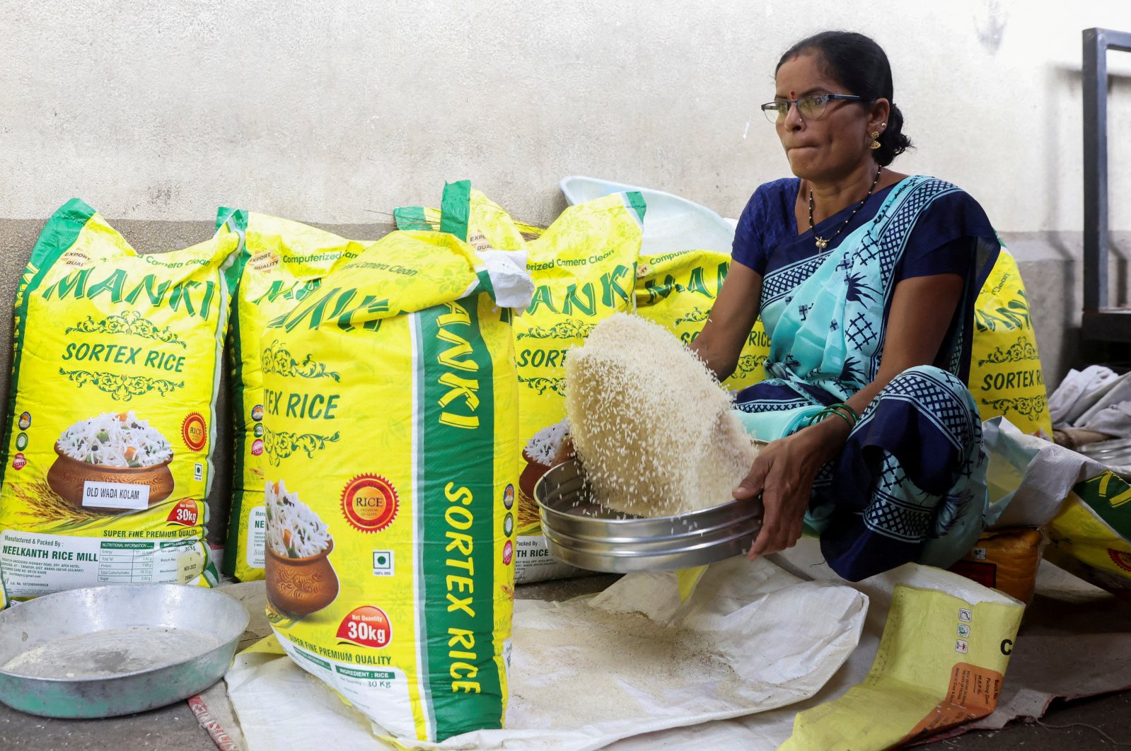 A woman cleans rice grains at a wholesale market in Navi Mumbai, India, Aug. 4, 2023. (Reuters Photo)