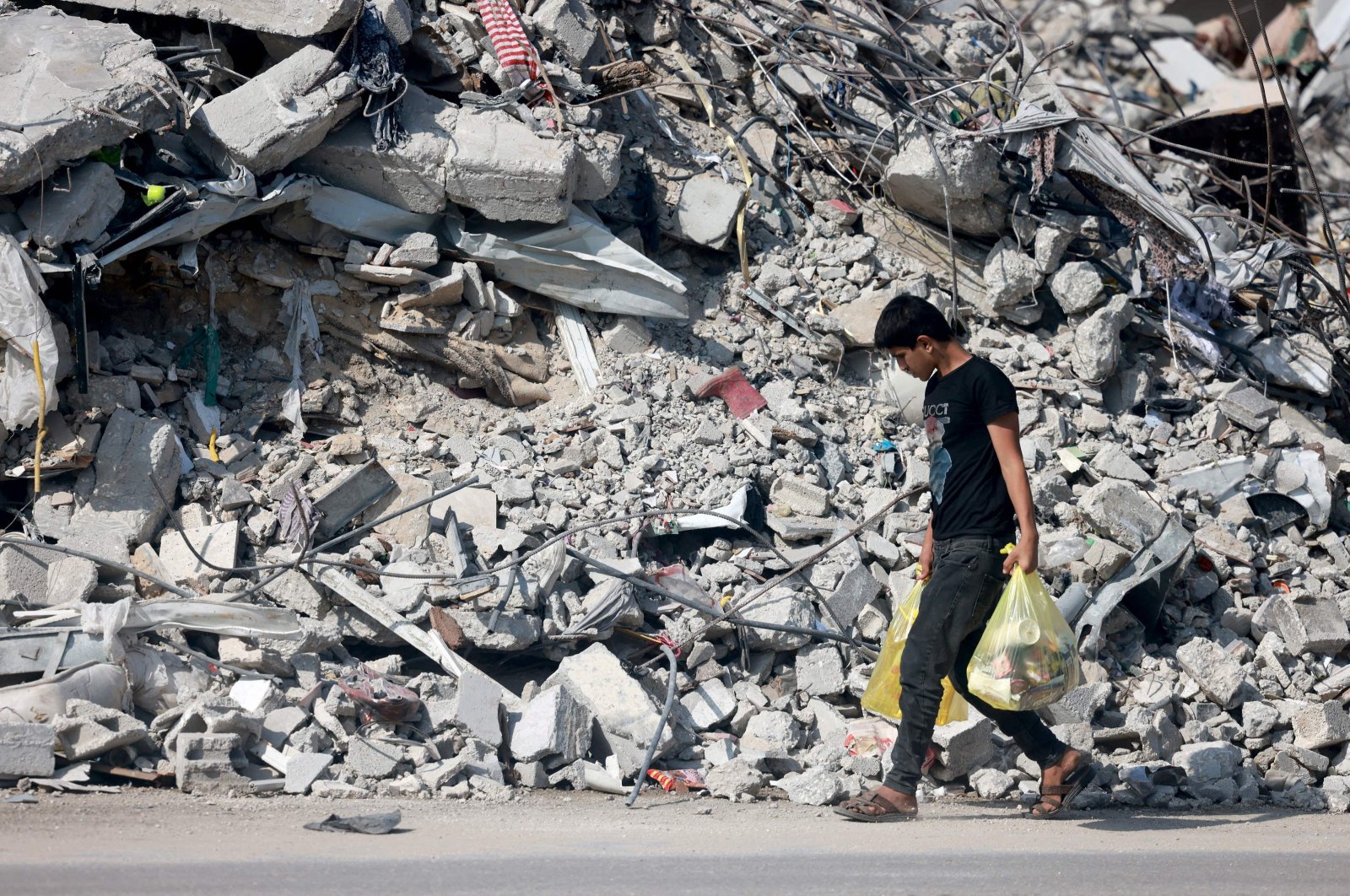 A youth carrying some belongings walks amid the rubble of destroyed buildings as people reach the central Gaza Strip via the Salah al-Din road on their way to the southern part of the Palestinian enclave on Nov. 5, 2023. (AFP Photo)