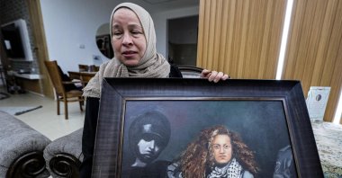 Nariman Tamimi, mother of detained Palestinian activist Ahed Tamimi, holds a framed painting depicting her daughter as she sits in their family home in the village of Nabi Saleh in the occupied West Bank, Palestine, Nov. 6, 2023. (AFP Photo)