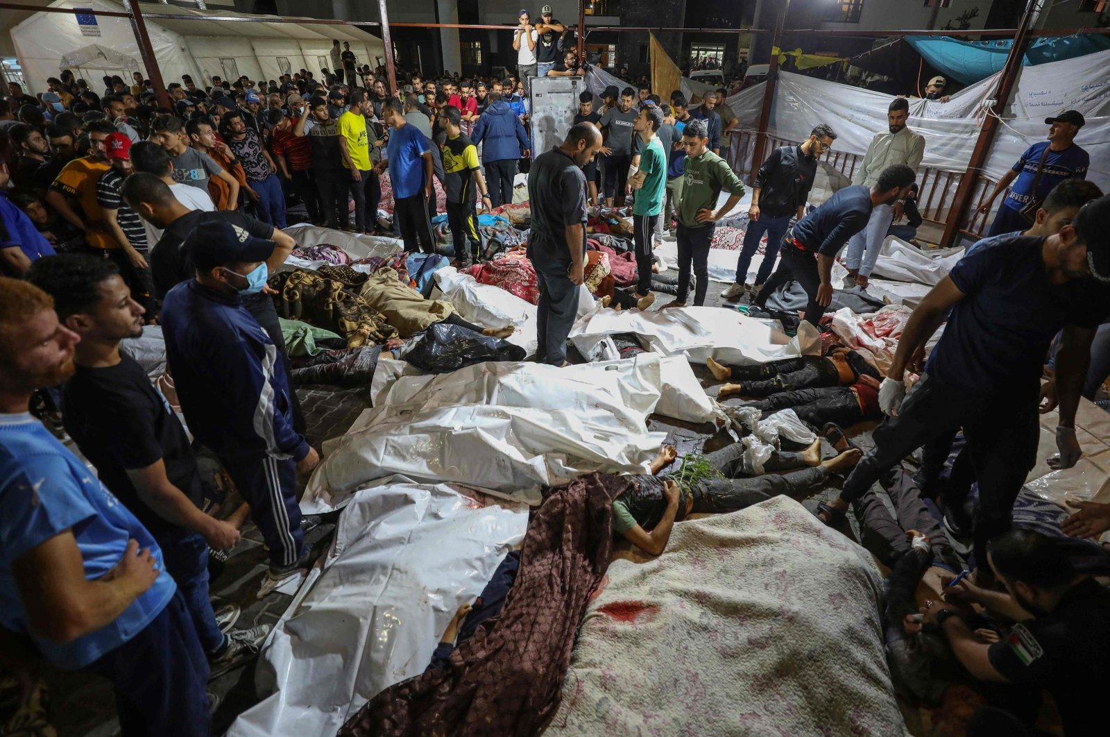 People gather around the bodies of Palestinians killed after a strike ripped through the Al-Ahli Baptist Hospital in central Gaza, after they were transported to Al-Shifa Hospital, the Gaza Strip, Palestine, Oct. 17, 2023. (AFP Photo)