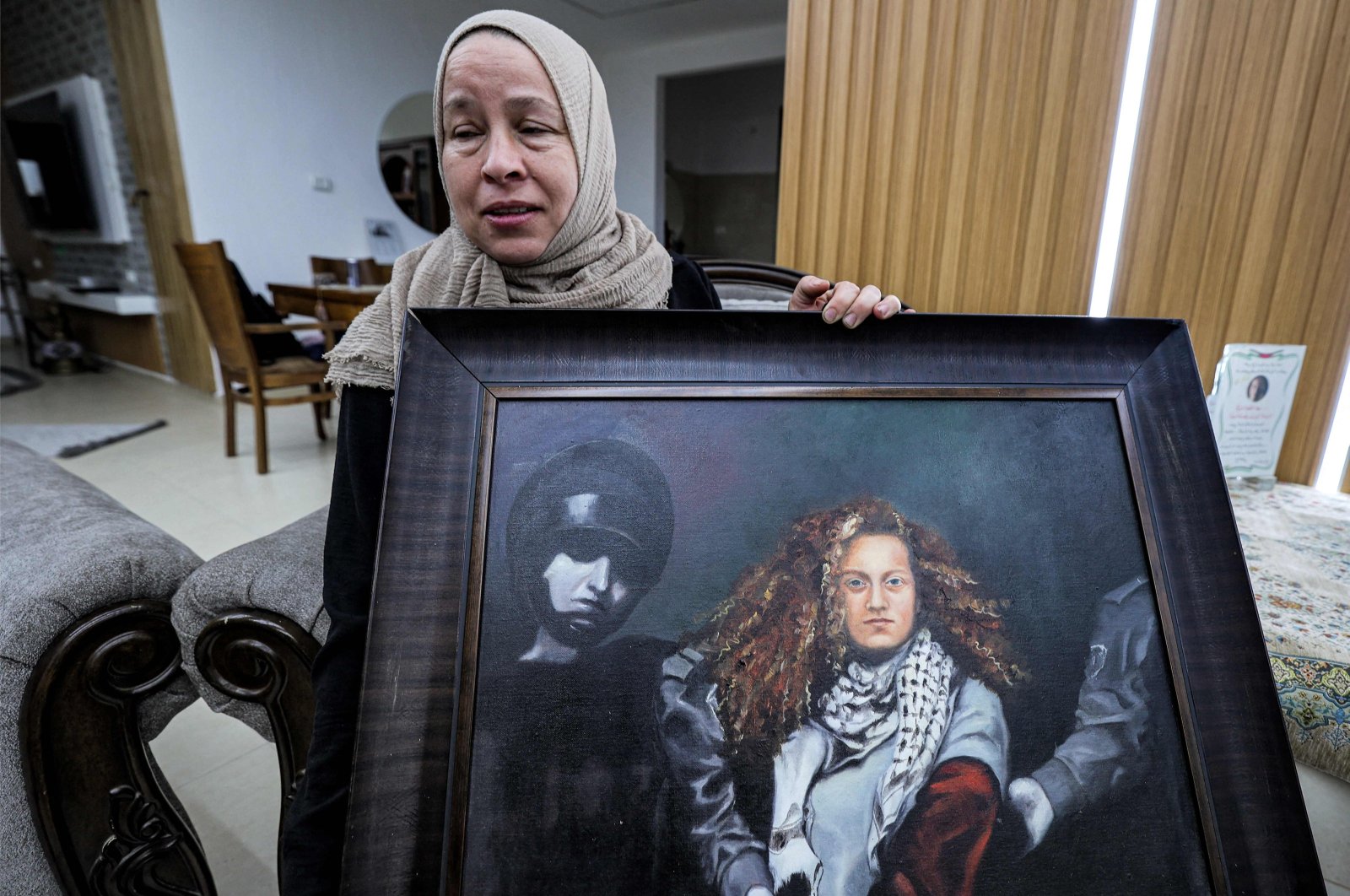 Nariman Tamimi, mother of detained Palestinian activist Ahed Tamimi, holds a framed painting depicting her daughter as she sits in their family home in the village of Nabi Saleh in the occupied West Bank, Palestine, Nov. 6, 2023. (AFP Photo)