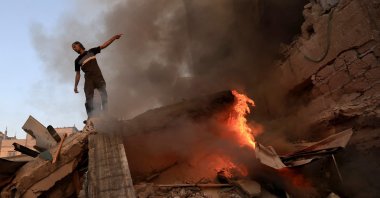 A Palestinian man gestures as he stands on the rubble of a collapsed building as a fire burns following a strike by the Israeli military on Khan Yunis in the southern Gaza Strip, Palestine, Nov. 4 , 2023, (AFP Photo)
