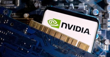 A smartphone with a displayed NVIDIA logo is placed on a computer motherboard in this illustration taken, March 6, 2023. (Reuters Photo)