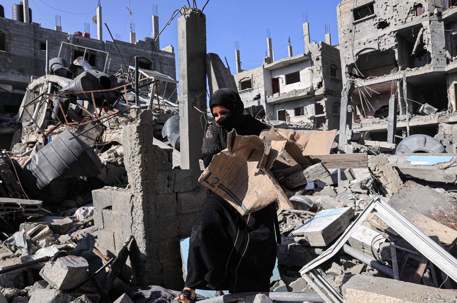 Amal al-Robayaa caries cardboard found amid the rubble of a building destroyed in Israeli bombing, to light a fire for making bread in Rafah in the southern Gaza Strip, Palestine, Nov. 7, 2023. (AFP Photo)