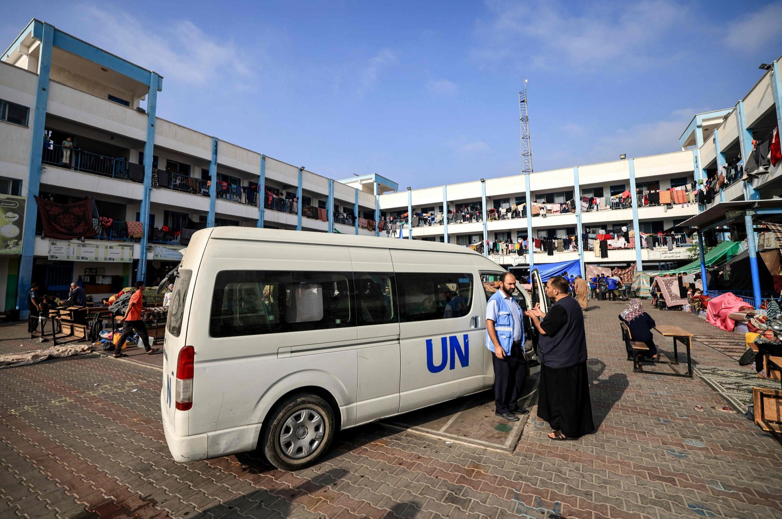 A man speaks with a worker of the UNRWA agency in the playground of an UNRWA-run school in Khan Yunis, southern Gaza Strip, October 25, 2023. (AFP Photo)