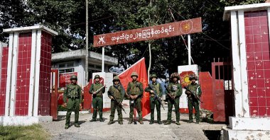 Members of the Myanmar National Democratic Alliance Army pose for a photograph in front of the seized army's infantry battalion in Kunlong, Myanmar, Nov. 12, 2023. (AP Photo)