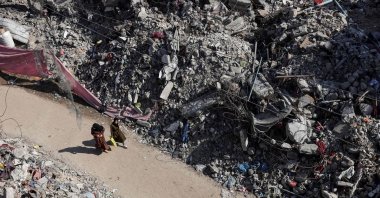 Two Palestinian women walk past buildings destroyed following the Israeli bombardment of Gaza, in Bureij in the central Gaza Strip, on Nov. 14, 2023. (AFP Photo)