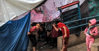 Children take shelter from the rain under a tent at a school run by the United Nations Relief and Works Agency for Palestine Refugees in the Near East (UNRWA), in Rafah in the southern Gaza Strip, on Nov. 14, 2023. (AFP Photo)