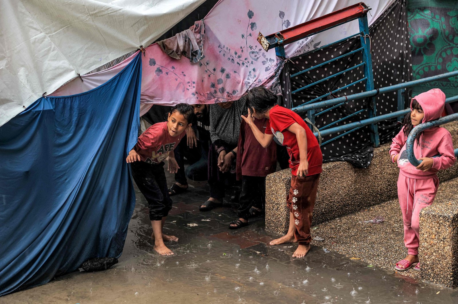 Children take shelter from the rain under a tent at a school run by the United Nations Relief and Works Agency for Palestine Refugees in the Near East (UNRWA), in Rafah in the southern Gaza Strip, on Nov. 14, 2023. (AFP Photo)