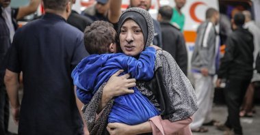 A Palestinian woman covered in dust rushes with her child in her arms into the hospital following the Israeli bombardment of Khan Yunis in the southern Gaza Strip, Palestine, Nov. 15, 2023. (AFP Photo)