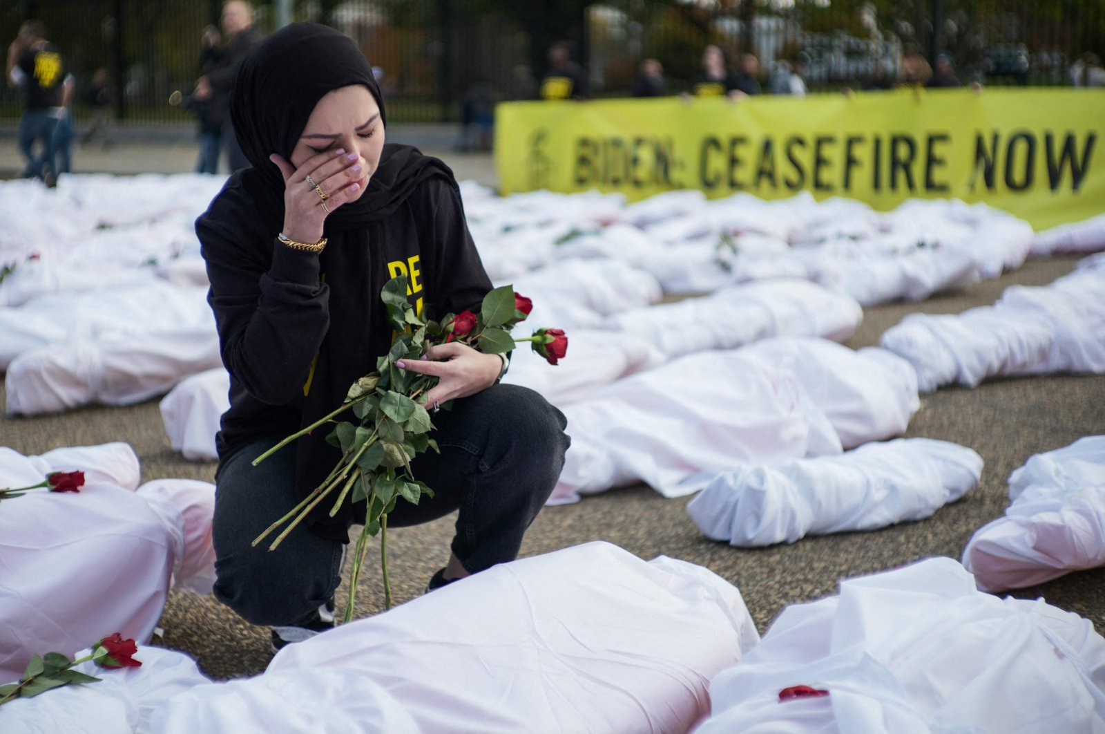 An activist wipes her eye while placing flowers on white-shrouded body bags representing victims in the Israeli-Palestinian conflict, in front of the White House, Washington, D.C., U.S., Nov. 15, 2023. (AFP Photo)