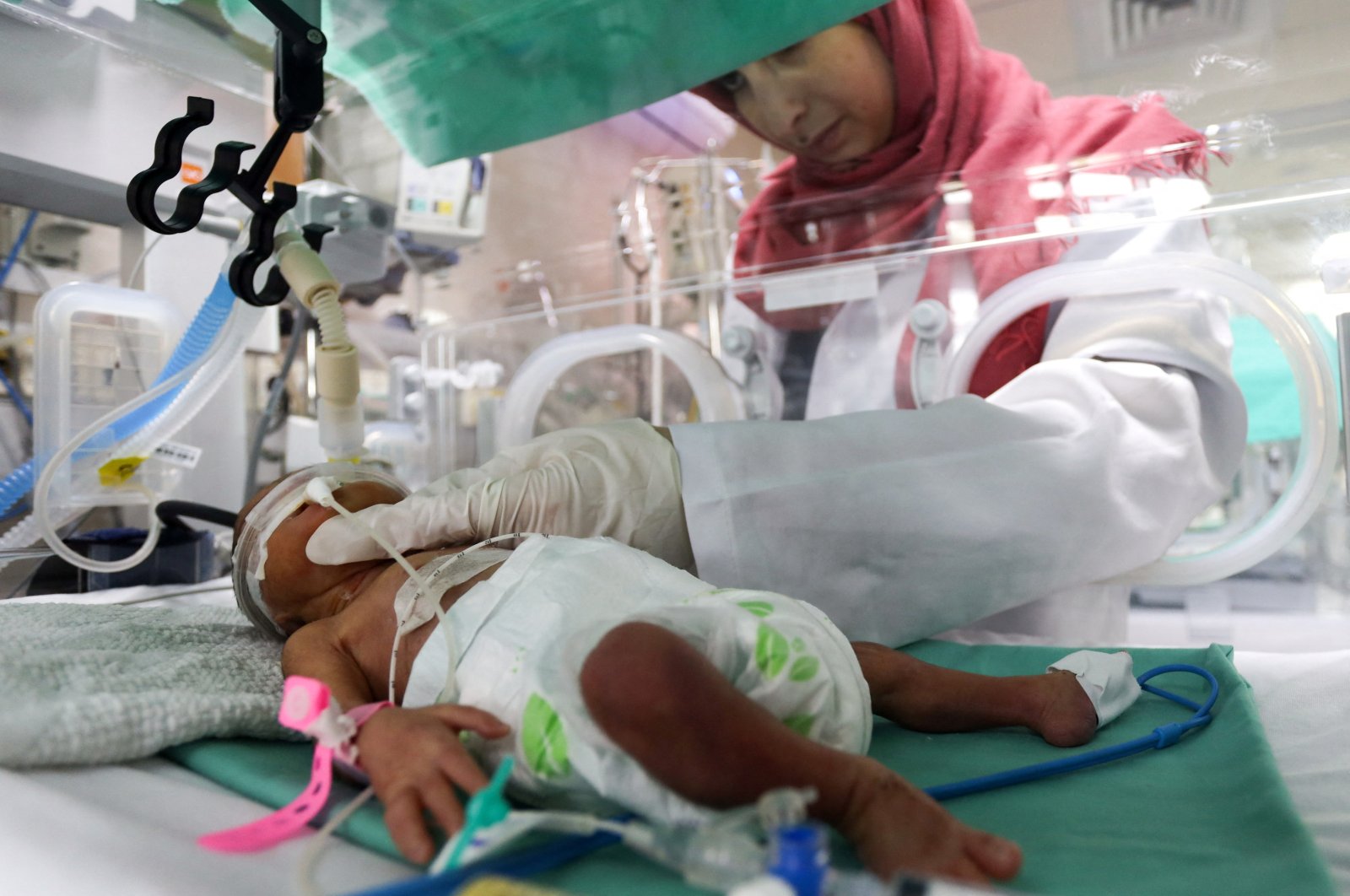 A medical worker assists a premature Palestinian baby who lies in an incubator at the maternity ward of Shifa Hospital, which according to health officials is about to shut down as it runs out of fuel and power, as the conflict between Israel and the Palestinian Islamist group Hamas continues, Gaza City, Palestine, Oct. 22, 2023. (Reuters Photo)