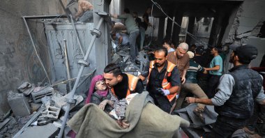 Palestinians carry an injured person as rescuers search the rubble of a building for survivors following Israeli bombardment in Khan Younis in the southern Gaza Strip on Nov. 18, 2023. (AFP Photo)