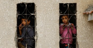 Palestinian children look out from a window with a grill at the site of Israeli strikes on houses, in Khan Younis, in the southern Gaza Strip, Nov. 9, 2023. (Reuters Photo)