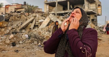 A Palestinian woman reacts as people inspect the damage following Israeli strikes on Rafah, on the southern Gaza Strip, on November 20, 2023, amid continuing battles between Israel and the militant group Hamas. (Photo by Mohammed ABED / AFP)