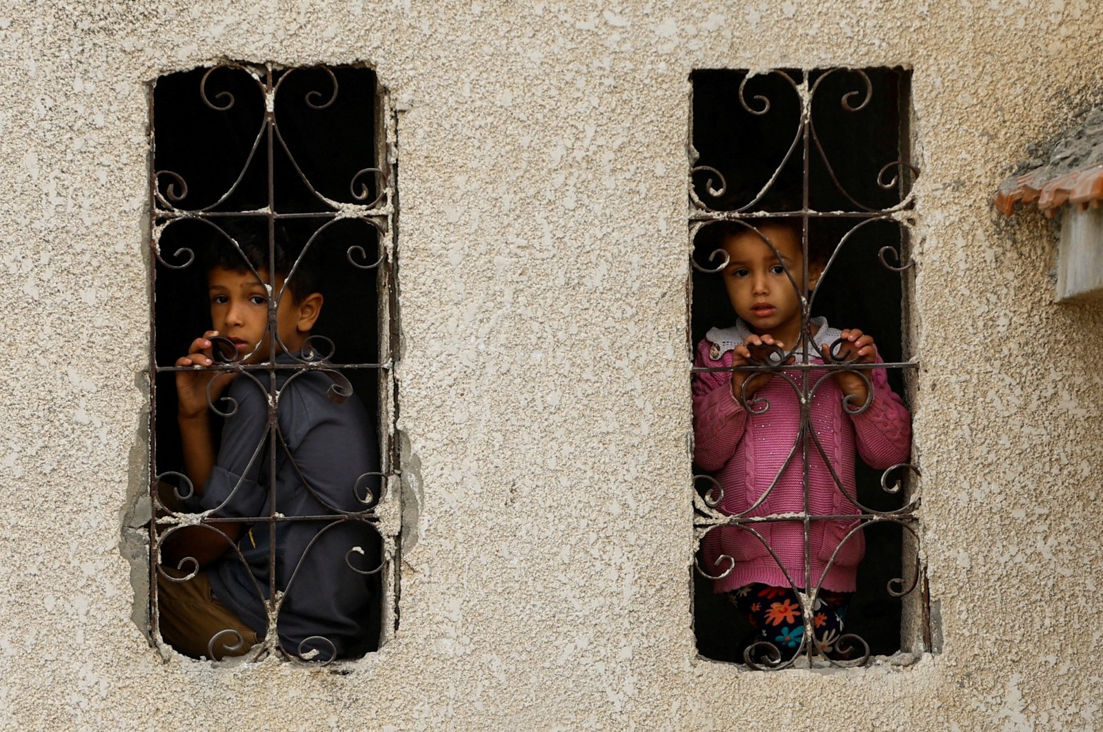 Palestinian children look out from a window with a grill at the site of Israeli strikes on houses, in Khan Younis, in the southern Gaza Strip, Nov. 9, 2023. (Reuters Photo)