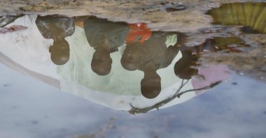 Children&#039;s reflections are seen in flood water outside the Al-Hidaya camp for the internally displaced people, Mogadishu, Somalia, Nov. 19, 2023. (Reuters Photo)