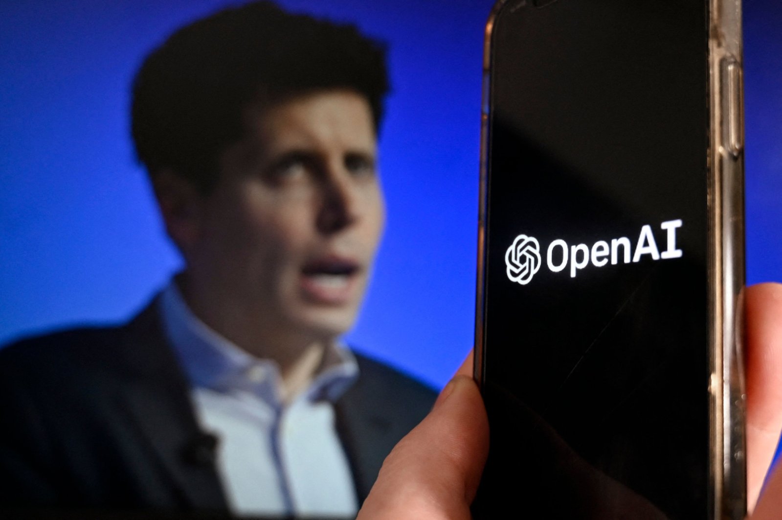 This illustration photo shows a smartphone screen displaying the logo of OpenAI juxtaposed with a screen showing a photo of former CEO Sam Altman, Arlington, Virginia, U.S., Nov. 20, 2023 (AFP Photo)