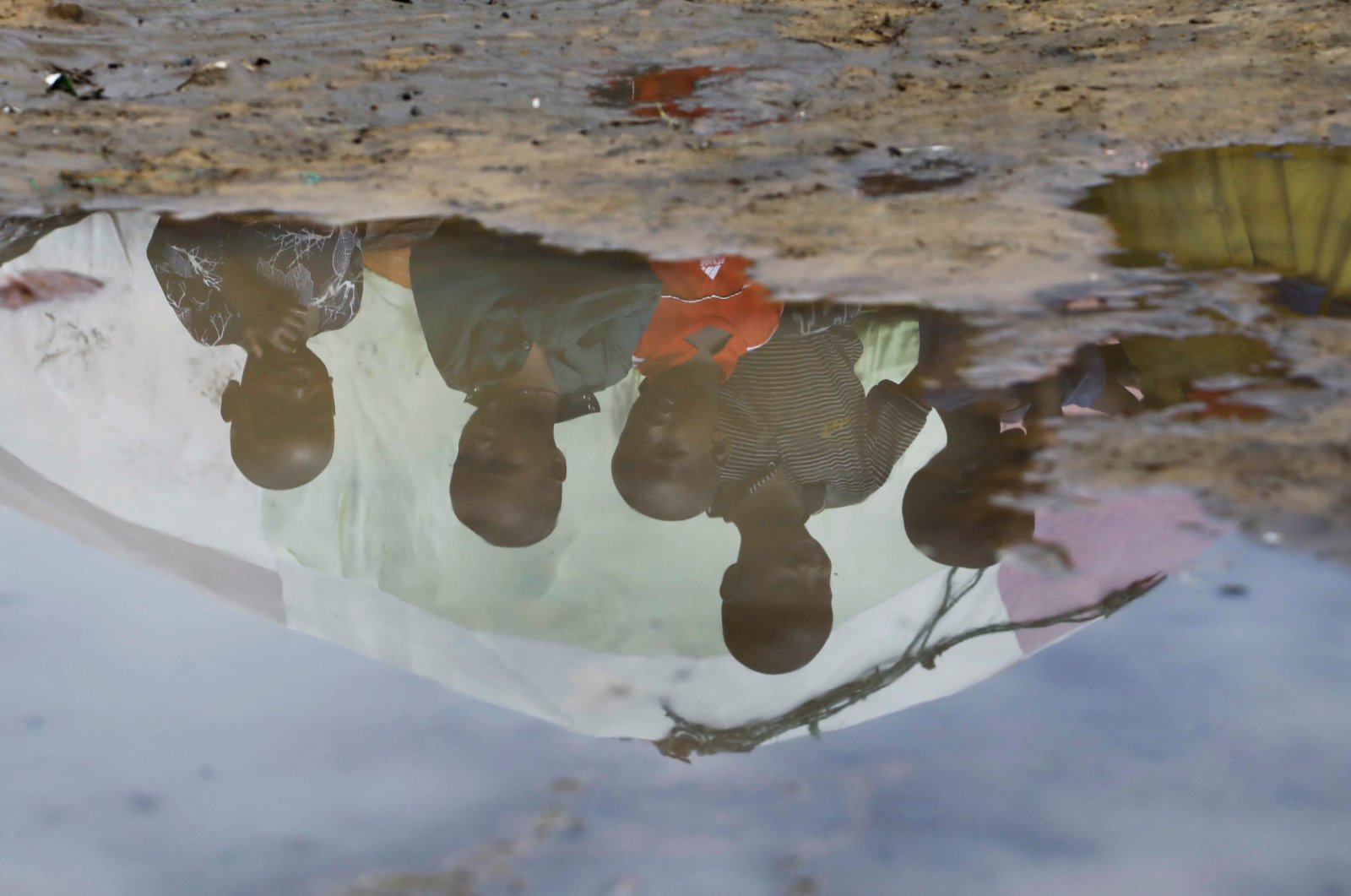 Children&#039;s reflections are seen in flood water outside the Al-Hidaya camp for the internally displaced people, Mogadishu, Somalia, Nov. 19, 2023. (Reuters Photo)